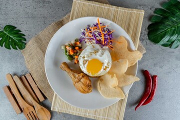 Traditional Indonesian Chicken Fried Rice Served on White Plate with Pickles and Crackers