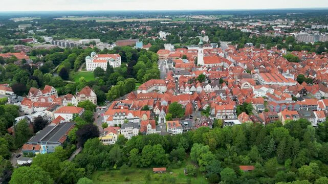 Aerial view of the terracotta rooftops and white facades of Celle Castle and the church contrasting against the lush green trees, Celle, Lower Saxony, Germany.