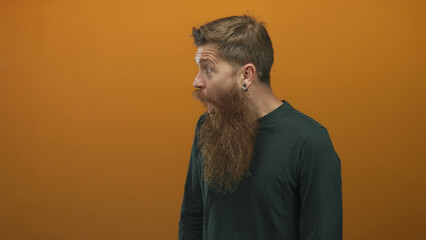 Man with open mouth in orange studio setting wearing dark shirt, eyes widened in astonishment as he...