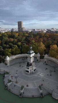 Aerial view of the Monument to Alfonso XII, a landmark in Parque Retiro, with autumn colors blending with the city skyline, Parque Retiro, Community of Madrid, Spain.