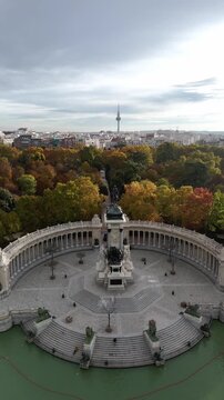 Aerial view of the monument to Alfonso XII surrounded by trees with autumn colors, standing majestically in the Parque del Retiro, Madrid, Community of Madrid, Spain.