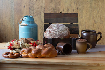Traditional bakery products no. 8 in an organized composition. Bread, loaves, rolls, croissants, pretzels, challah, ears of grain, baked goods, a blue metal watering can, traditional table decoration