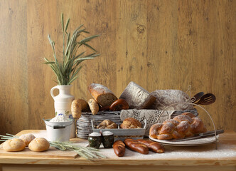 Traditional bakery products no.1 in an arranged composition. Bread, slices of bread, rolls, croissants, pretzels, challah, ears of grain, baked goods, porcelain jug, sugar bowl, traditional decoration