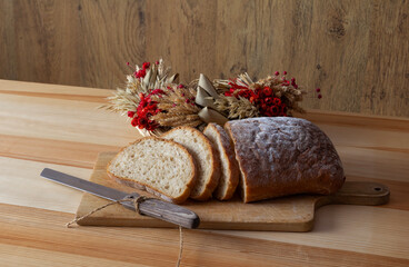 freshly sliced bread on a wooden cutting board no. 1, bread cutting knife, delicious breakfast, decorative bouquet of grains, kitchen knife for slicing bread