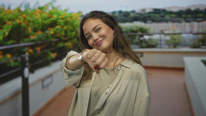 Woman smiling outdoors in a park showing a confident gesture with her fist, surrounded by greenery...