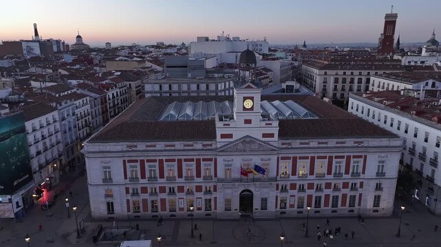 Aerial view of the building in Puerta del Sol with its clock tower and Spanish flags, set against the city skyline at dusk, Madrid, Puerta del Sol, Spain.