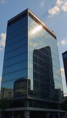 Obraz premium A modern glass building reflects the urban sky and clouds in an abstract architectural detail