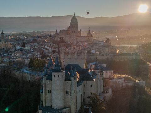 Aerial view of the majestic Alc&Atilde;&iexcl;zar de Segovia, a medieval castle bathed in the warm glow of sunrise, stands proudly against a backdrop of distant mountains, Segovia, Castilla y Le&Atilde;&sup3;n, Spain.
