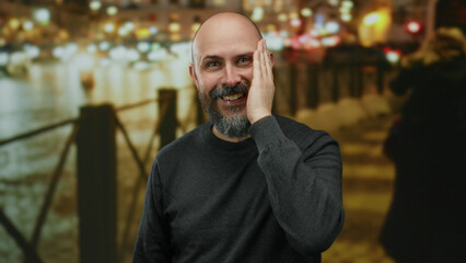Fototapeta premium Man with beard laughing on urban street at night with blurred lights in background, creating a lively and joyous cityscape ambiance.