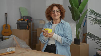Woman enjoying coffee in new home living room surrounded by moving boxes and plants, creating a cozy ambience of starting fresh in a bright, inviting space.