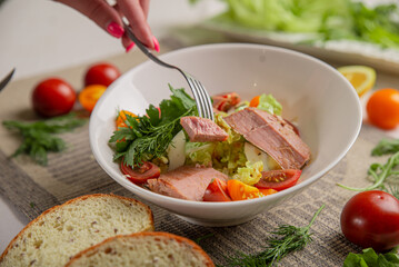 Salad with tuna and vegetables in a white bowl close-up