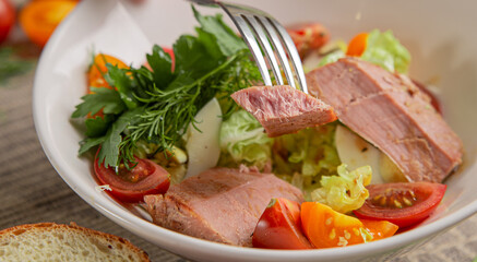 Salad with tuna and vegetables in a white bowl close-up