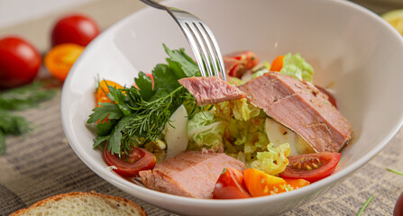 Salad with tuna and vegetables in a white bowl close-up