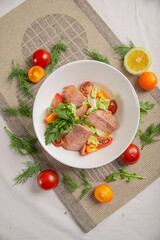 Salad with tuna and vegetables in a white bowl close-up