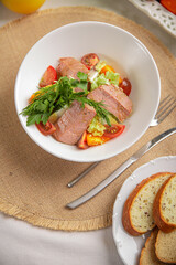 Salad with tuna and vegetables in a white bowl close-up