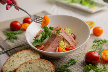 Salad with tuna and vegetables in a white bowl close-up