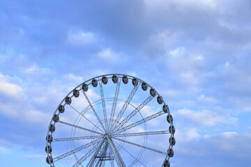Scenic Ferris wheel structure against cloudy sky, symbol of travel, leisure and panoramic views.