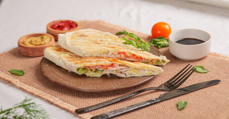 Lavash with vegetables and meat baked on a grill on a white plate on a served table