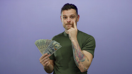 Fototapeta na wymiar Young hispanic man with tattoos holding us dollars against a purple background, embodying a modern confident attitude with subtle gestures of thought and contemplation.