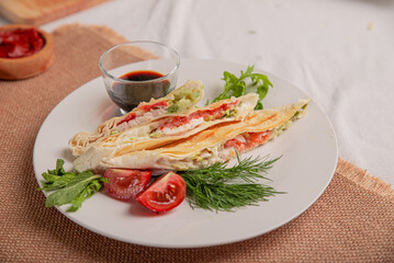 Wheat flatbread with vegetables and meat baked grilled on white plate on served table