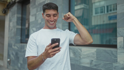 Man holding smartphone and tapping screen with finger on street wearing white t shirt and focused gaze on display; excitement.