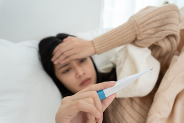 Young Asian woman having high fever while checking body temperature, female sneezing and runny nose...