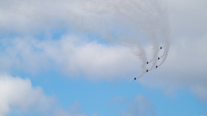Aerobatic planes turning in the sky with smoke trails
