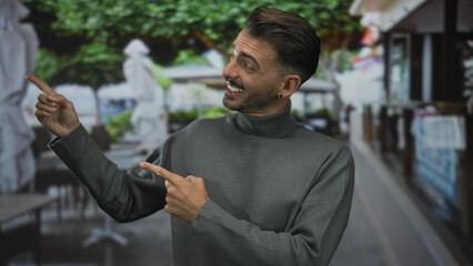 Man wearing gray turtleneck points finger at outdoor terrace table in street restaurant; cheerful...