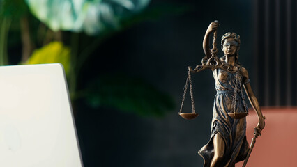 Bronze statue of Lady Justice holding scales, symbolizing law and fairness, positioned on a desk...