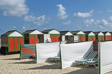 Row of red and green beach huts and canvas to shelter from the wind, the typical beach equipment of the Belgian coast at De Panne, Belgium.