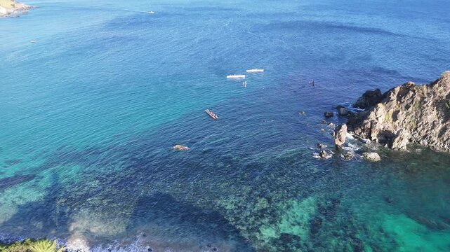 Turistas remam em canoas sobre as &aacute;guas cristalinas da praia da Concei&ccedil;&atilde;o, com o ic&ocirc;nico Morro do Pico compondo o cen&aacute;rio natural ao fundo