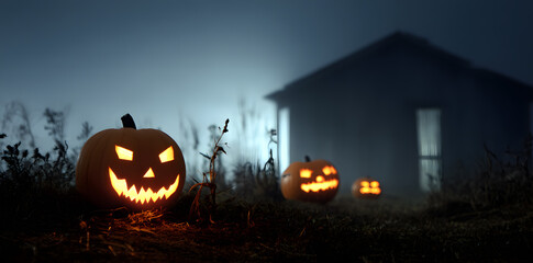 Scary jack o’lanterns glowing outside in a dark misty Halloween night.