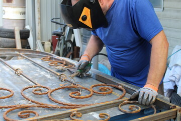 A man makes beautiful gates from forged metal and welding.