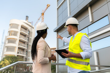 Male Construction engineer showing building project to female architect on construction site