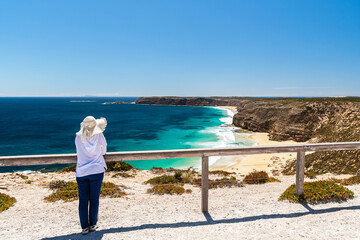 A woman with a white hat looks at the scenic coastline of Innes National Park