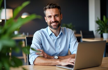Businessman working on laptop in modern office environment with plants and warm lighting