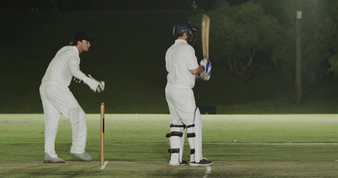 Male cricketers reacting to ball, hitting shot, keeper appealing dismissal under lights, copy space