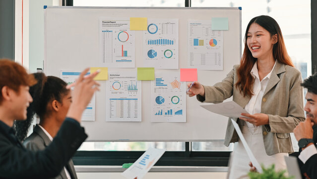 Smiling presenter explains graphs and reports to a diverse team during a collaborative planning session