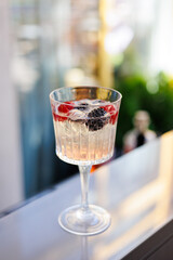 Refreshing sparkling drink with raspberries outdoors, Elegant glass of sparkling water with fresh raspberries on a sunny day, placed on a wooden table in a garden setting.
