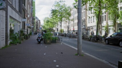 Blurred amsterdam street scene with bokeh effect capturing urban architecture, greenery, and bicycles along a quiet city sidewalk under a clear sky.