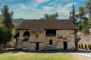 Historic stone building stands proudly amidst greenery in a serene landscape under a bright blue sky