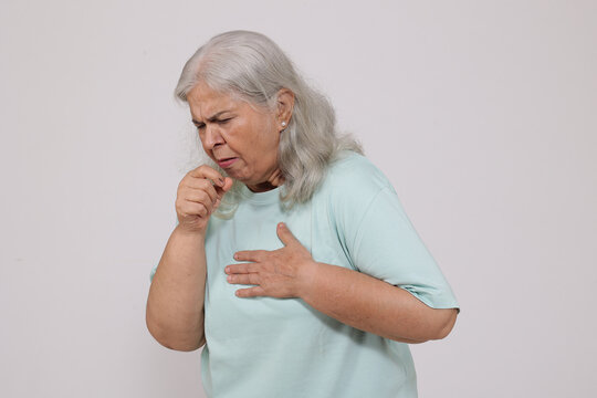 Portrait of senior indian elderly woman coughing - isolated on white background