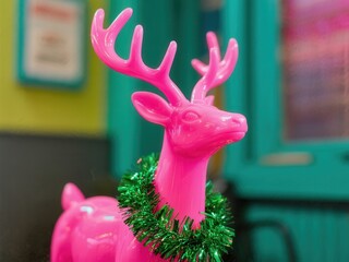 Vibrant Christmas pink reindeer statue with green garland in colorful setting
