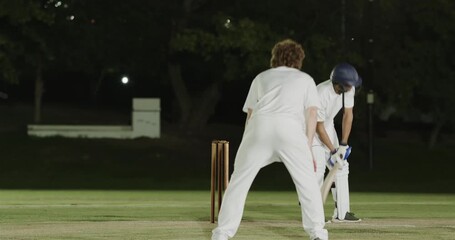 Appealing for wicket after stumps catch, bowler and diverse male team celebrating under floodlights