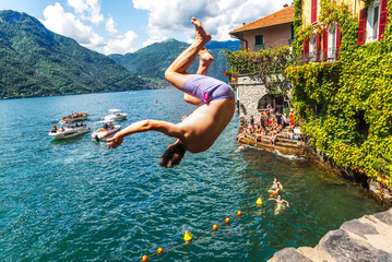  Young people jumping into the water from the stone bridge in Nesso. Jumping from Nesso Bridge. Lake Como, Italy.