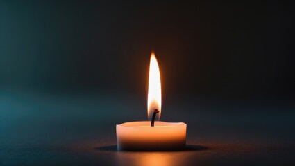 Fototapeta premium A single lit candle against a dark background.