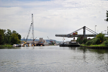Riverside Industrial Loading Cranes Reflected in Calm Waters of River on Sunny Day