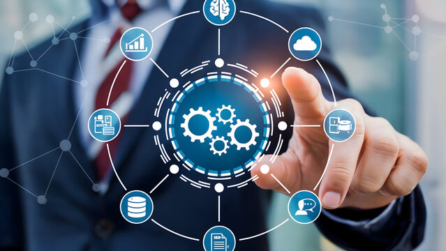 A businessman pointing at a digital interface with gears and connected business icons around it