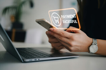 A person's hand is holding a phone in front of a laptop and payment is successful