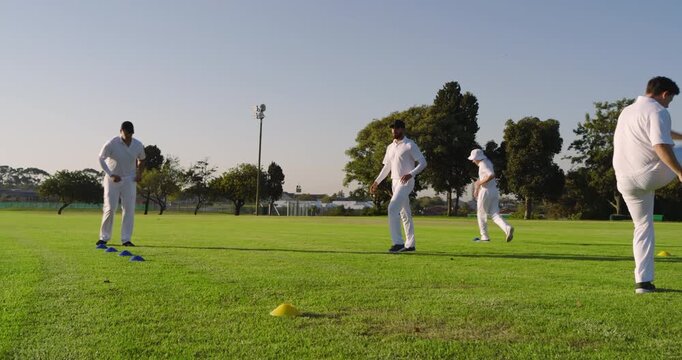 Rotating turns, Diverse male teammates jogging to cones on cricket field doing drills for footwork